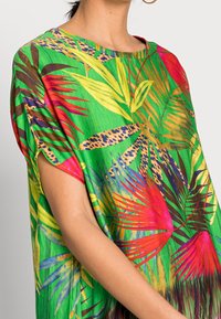 Top ampio e a maniche corte di un verde vivace, caratterizzato da motivi di foglie tropicali multicolori, arricchito da dettagli con stampa animale.