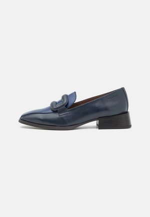 Mocassin en cuir bleu marine avec petit talon carré et détail de sangle repliée sur le dessus, incliné pour montrer le côté extérieur.