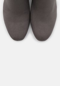 Stivaletti grigi a punta con caviglia, caratterizzati da una texture morbida e una finitura liscia, con design slip-on e senza hardware o dettagli visibili.