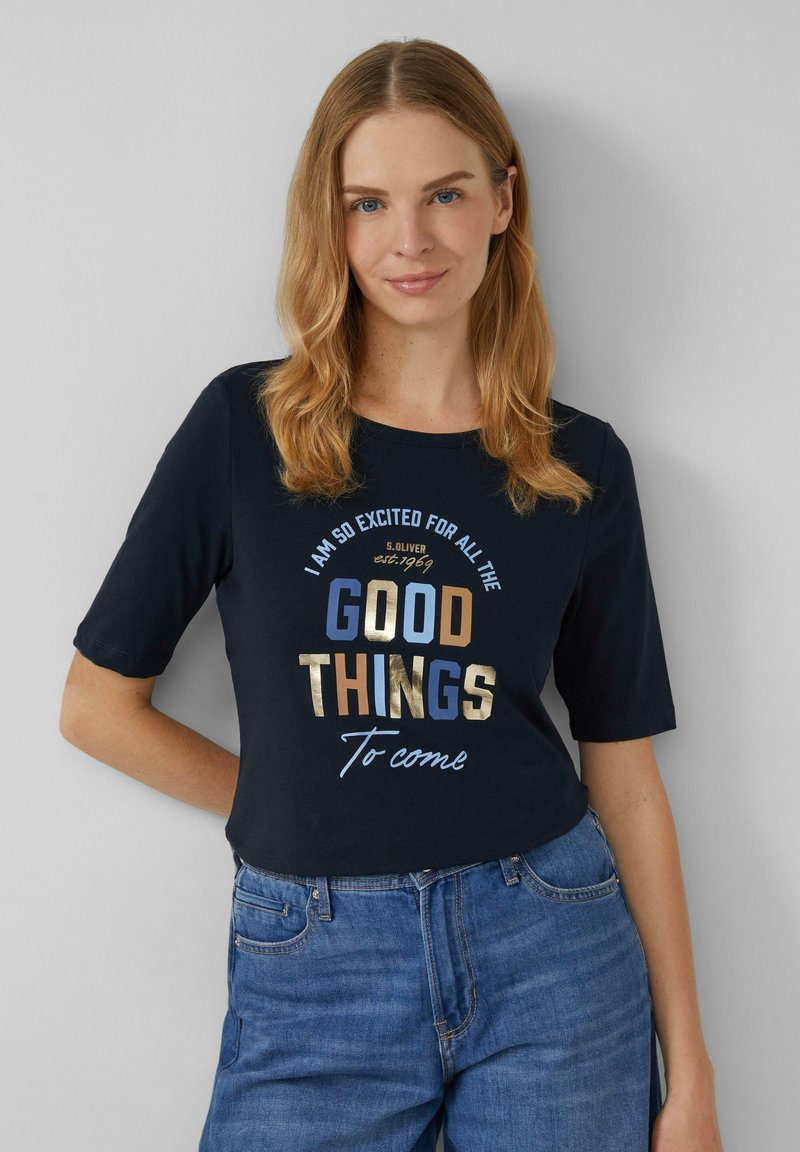 T-shirt en coton bleu marine à manches courtes, avec un texte métallique en or, bleu et marron : "JE SUIS TELLEMENT EXCITÉ POUR TOUTES LES BONNES CHOSES À VENIR."