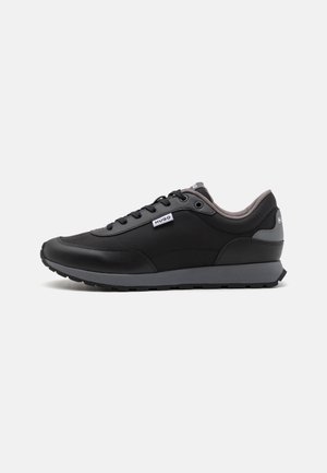 Black athletic sneakers featuring a smooth synthetic upper, grey accents, lace closure, and textured rubber outsole for grip.