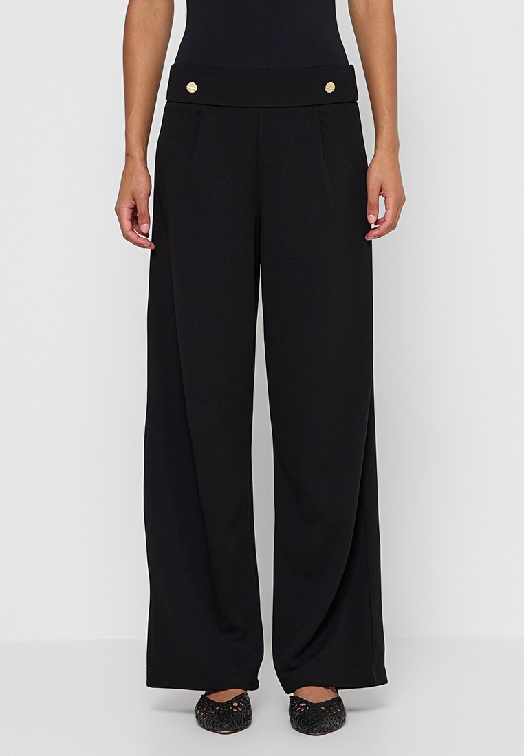 Zwarte wijde broek met een platte tailleband, voorzien van twee gouden knopen aan de voorkant. Gemaakt van zachte stof met subtiele plooien.