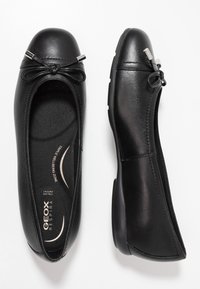 Bailarinas de cuero negro con punta redonda, detalle de lazo en la parte delantera y plantilla texturizada. Cuenta con una suela de goma elegante y de perfil bajo.