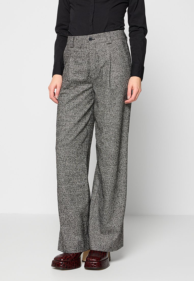 Graue und schwarze gemusterte lässige Weitbein-Hosen mit hoher Taille, Falten und entspannter Passform, kombiniert mit glänzenden bordeauxfarbigen Schuhen.