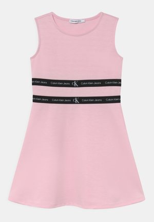 Różowa sukienka bez rękawów, wykonana z miękkiego materiału, o rozkloszowanym kształcie i z dwiema czarnymi taśmami z logo "Calvin Klein Jeans" w okolicy talii.