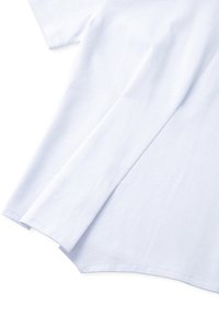 Camiseta blanca de manga corta en suave material de algodón. Presenta un dobladillo redondeado con detalles de costura. Textura suave, ajuste relajado.