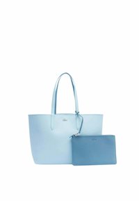 Borsa a tracolla in pelle azzurro chiaro con due manici, dotata di una piccola pochette con zip abbinata. Texture liscia, design minimalista, logo Lacoste visibile.