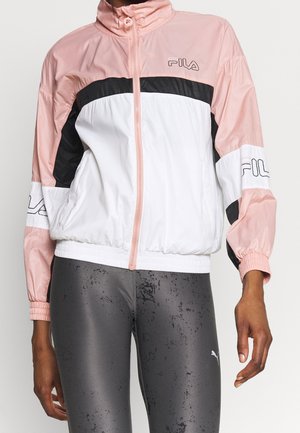 Personne portant une veste zippée FILA rose, blanche et noire avec des poignets élastiques et un legging noir brillant.