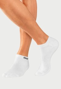 Weiße Knöchelsocken aus weicher Baumwolle, mit einem gerippten Bündchen und schwarzem Logo-Detail an der Seite. Glatte Textur, niedriger Schnitt.