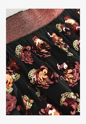 Falda negra con una cinturilla elástica texturada en color oro rosa. Cubierta de lentejuelas en capas en tonos de rosa, oro y burdeos con patrones florales.