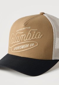 Καφέ και μαύρο καπέλο μπέιζμπολ με λευκή πλέξη στο πίσω μέρος και κεντημένο λογότυπο «Authentic Columbia Sportswear Co.» στο μπροστινό πάνελ.