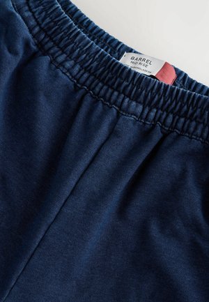 Marineblaue, mittelhohe Shorts mit elastischem Bund. Weicher Stoff und ein angenähtes Etikett am Bund zur Markenidentifikation.