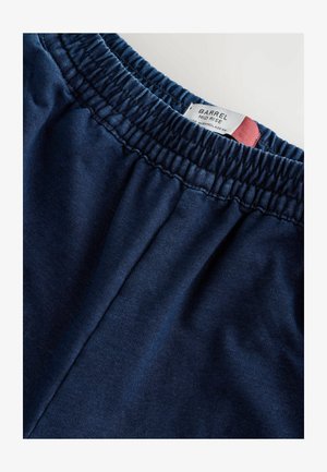 Shorts bleu marine taille mi-haute avec une taille élastique. Texture de tissu douce et une étiquette cousue sur la taille pour l'identification de la marque.