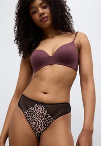 Καφέ μαξιλαρωτό σουτιέν με ρυθμιζόμενους ιμάντες, συνδυασμένο με μαύρο εσώρουχο με λεοπάρ τύπωμα και δίχτυ, ψηλόμεσο, με πουά λεπτομέρειες.