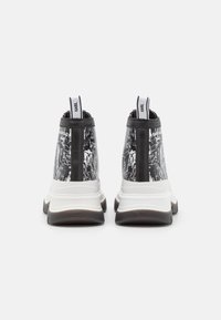 Sneaker alte in bianco e nero con una finitura testurizzata, suola intermedia bianca e linguetta sul tallone con il marchio. Suola in gomma resistente.