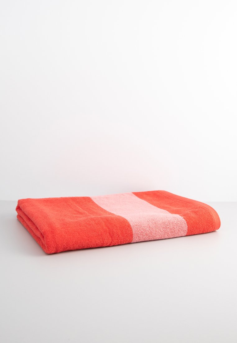 Toalla de algodón en un vibrante color naranja con una amplia franja rosa. Tejido suave y texturizado; doblada de manera ordenada con bordes limpios y una superficie lisa.