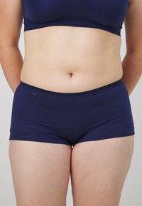Navy blue boyshorts made of soft fabric with a smooth texture. Features a waistband with subtle stitching and a small logo tag on the front.