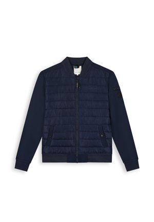 Marineblaue Bomberjacke mit gesteppter Vorderseite, Reißverschluss, zwei Druckknopftaschen, Reißverschlusstasche am linken Ärmel sowie gerippten Bündchen und Kragen.