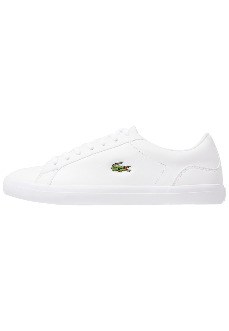 Baskets basses blanches avec lacets blancs, tige en cuir lisse et logo crocodile vert sur le côté.