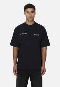 Zwarte katoenen t-shirt met een relaxte pasvorm. Heeft witte geborduurde tekst op de borst: "Life Without Project" en "GFN." Eenvoudig ontwerp.