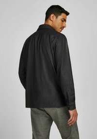 Schwarze Button-Down-Bluse aus strukturiertem Stoff, mit normalem Kragen und langen Ärmeln. Verfügt über Knopfdetails an den Manschetten und einen lässigen Schnitt.
