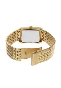 Montre en acier inoxydable doré avec un boîtier rectangulaire, un bracelet à maillons métalliques et une fermeture à clip. Le dos présente une gravure de la marque et des informations sur la résistance à l'eau.