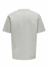Camiseta de algodón gris claro con mangas cortas y cuello redondo. Presenta una textura suave y un diseño simple y minimalista.