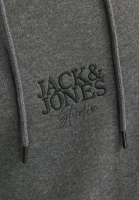 Sudadera con capucha de color gris oscuro con un tejido texturizado, que presenta un logotipo bordado de "JACK & JONES" en negro y detalles de cordones en la capucha.