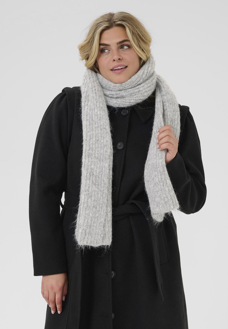 Sciarpa grigia chiara, con texture, realizzata in morbido materiale, con un design a costine, avvolta attorno al collo, abbinata a un cappotto nero con bottoni.