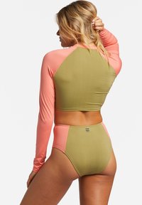 Langärmlige Rashguard und hochgeschnittenes Bikini-Set. Olivgrüner Körper mit pinken Ärmeln und Akzenten. Glattes, dehnbares Material mit Logodetail.