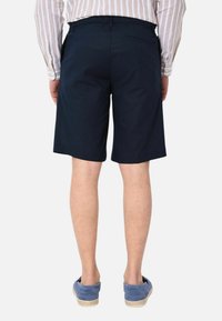 Pantaloni corti blu navy realizzati in tessuto con una texture liscia. Presentano una vestibilità morbida, lunghezza fino a metà coscia e una tasca posteriore con un design discreto.