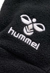 Svart fleece-tyg med en vit broderad logotyp som visar stiliserade former och ordet "hummel" nedanför. Mjuk textur, närbild.