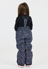 Barnens vadderade overaller i marinblått tyg med ett blommönster i rosa och grönt. Har justerbara remmar och en säker passform.