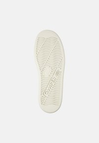 Gummisulor i off-white, med ett vågigt mönster, en central logotyp och släta kanter för grepp och flexibilitet.