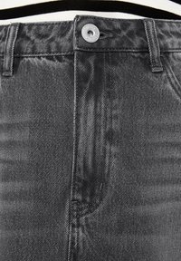 Schwarze Denim-Jeans mit klassischem Fünf-Taschen-Design, metallischem Knopfverschluss und subtiler Textur mit einem leichten Glanz.