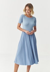 Vaaleansininen mekko, jossa on istuva lyhythihainen yläosa ja pleatattu midi-hame. Valmistettu pehmeästä kankaasta, jossa on pyöreä pääntie ja hienovarainen tekstuuri.