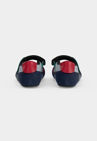 Paire de chaussures de sport basses avec des détails bleu marine, gris, sarcelle et rouge, vues de dos sur un fond blanc uni.