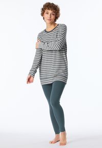 Randig långärmad tröja i grått och vitt, ihopparad med teal leggings. Tröjan har en rund halsringning och en avslappnad passform.