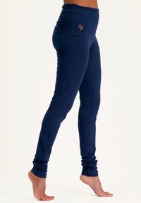 Marineblaue Sportleggings mit hohem Taillenbund, aus einem glatten, dehnbaren Material gefertigt. Mit Raffung am Knöchel.