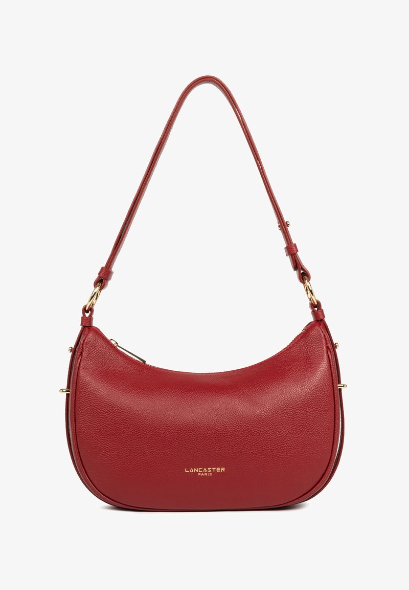 Sac à épaule en cuir rouge avec une forme incurvée, des accents en métal doré, une fermeture éclair et une bandoulière ajustable. Marquage visible sur le devant.