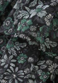 Bloemstof met een zwarte achtergrond en groene, witte en grijze bloemen en bladeren. Lichtgewicht, gestructureerd materiaal met gedetailleerde patronen.