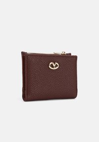 Portafoglio in pelle bordeaux con una texture granulosa, dotato di una tasca con zip e un accento del logo dorato sul fronte. Forma rettangolare compatta.