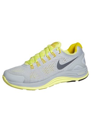Lysegrå og gul Nike løbesko med mesh-overdel, gule snørebånd, polstret sål og sort Swoosh-logo på siden.