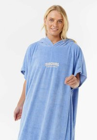 Poncho azul con capucha hecho de material suave y absorbente. Presenta un corte holgado y un logo en la parte frontal que dice "Rip Curl Surfing Company."