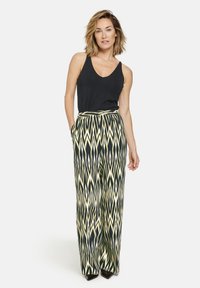 Black tank top paired with wide-leg trousers featuring a black, white, and yellow zigzag pattern. Trousers have a high waist and pockets.