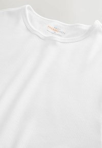 White ribbed t-shirt with a round neckline, made of soft material. Tag reads "NEXT THERMOGEN," indicating size M, made in Bangladesh.