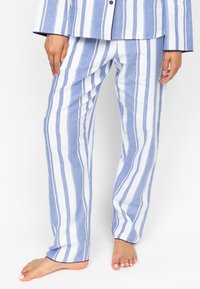 Gestreepte pyjama set in lichtblauw en wit, met lange, loszittende broeken van een gladde stof en contrasterende marineblauwe accenten.