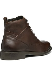Stivale alla caviglia in pelle marrone con punta rotonda, chiusura con lacci e tacco rinforzato. Presenta cuciture discrete e una texture liscia.