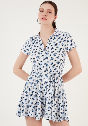 White short-sleeve dress with blue floral pattern, collar, button front, cinched waist, and flared skirt. Lightweight texture.
