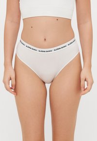 White high-waisted underwear with a black "BJÖRN BORG" logo on the elastic waistband; soft cotton fabric, smooth texture, simple design.